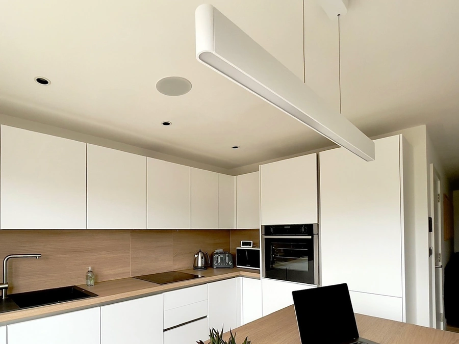 A handleless white kitchen with a Lithe Audio speaker set into the ceiling