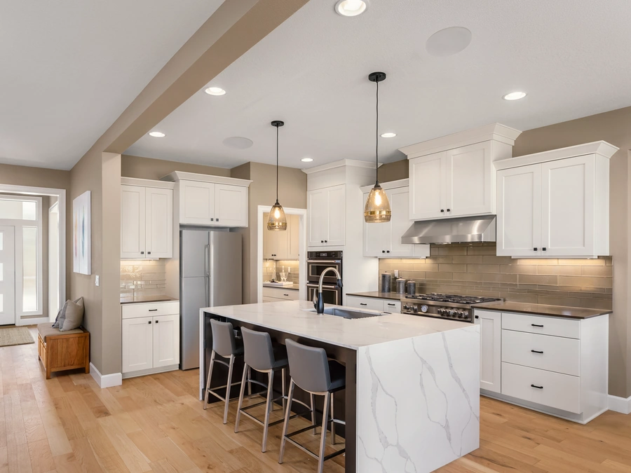 An open-plan kitchen with pendant lights and speakers set into the ceiling